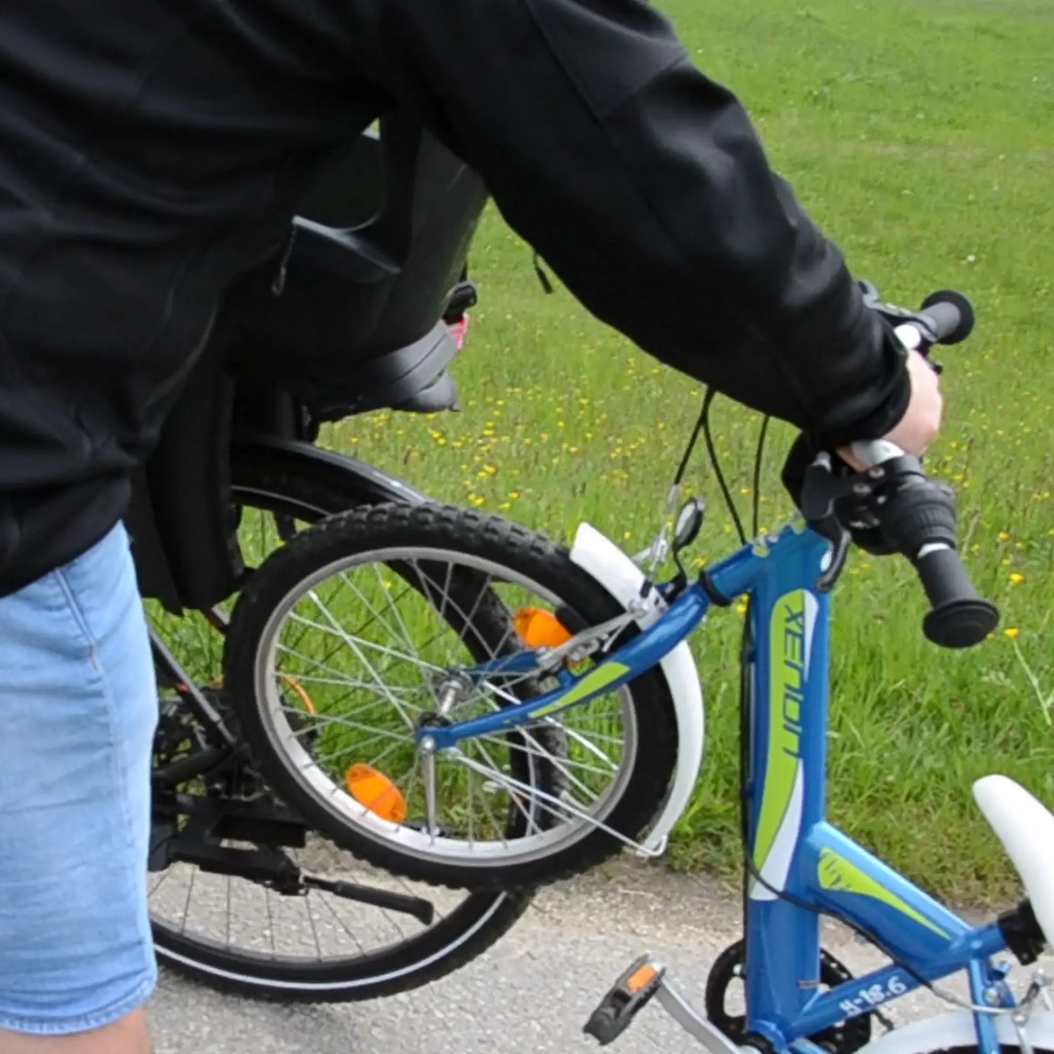 Der Vorderreifen vom Kinderfahrrad oder Laufrad wird vom Boden abgehoben und von oben in das Foaweida Mitnehmsystem eingeklickt. 